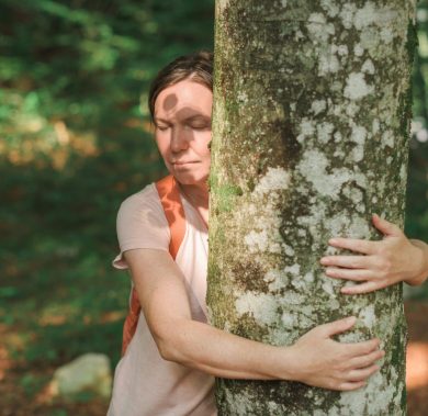 Woman is hugging tree trunk in forest, female environmentalist with her arms around the tree, selective focus